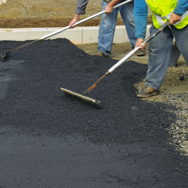 workers applying an asphalt coat to a street